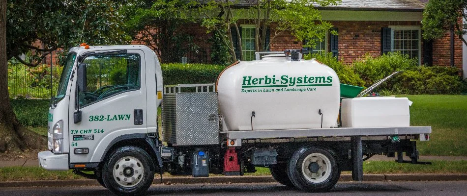 A professional weed control truck in front of a house in Memphis, TN.