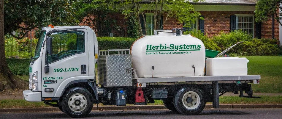 Professional weed control truck in Memphis, TN, parked outside a brick house.