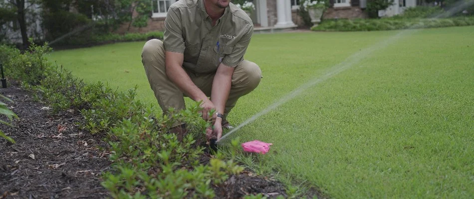 Tech adjusting a sprinkler head on a lawn in Brownsville, TN.